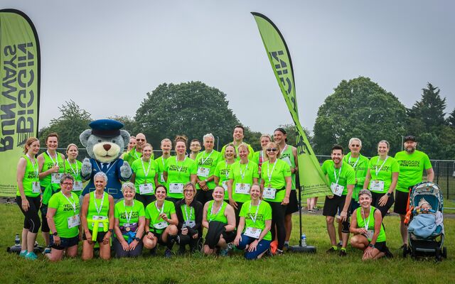 Group of runners posing after completing event in neon green jerseys