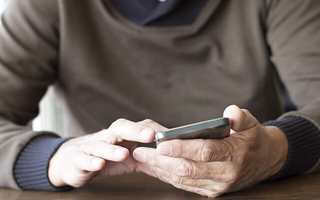 Man holding phone in hands wearing jumper