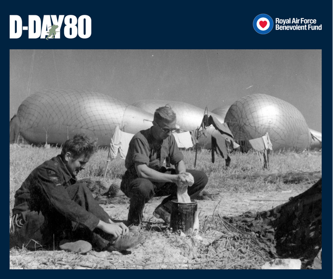 Two RAF servicing commandos take time to wash their laundry at an airfield in Normandy against a backdrop of barrage ballons, late June 1944.