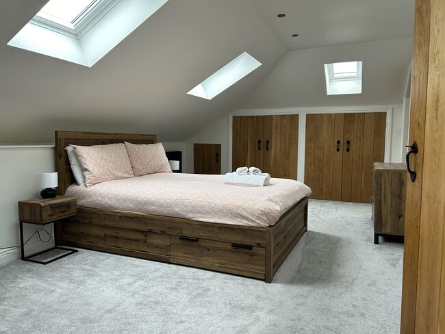 A carpeted bedroom with large bed and sky lights