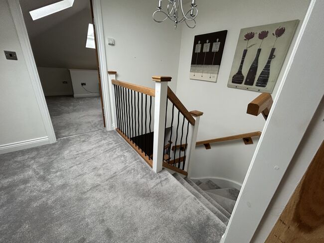 A carpeted hallway featuring a staircase