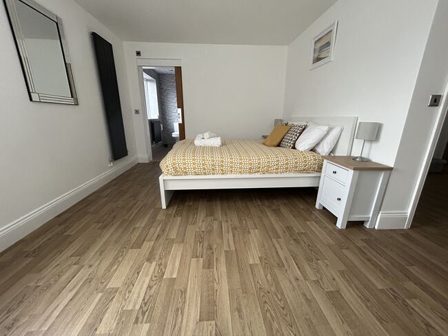 A large bedroom with bed and wooden floors