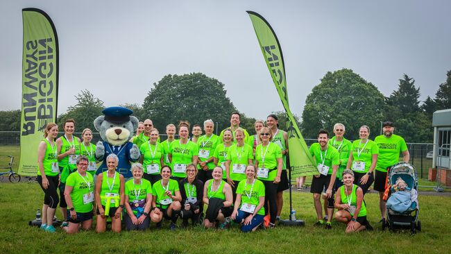 Group of runners posing after completing event in neon green jerseys