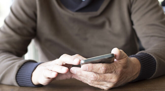 Man holding phone in hands wearing jumper