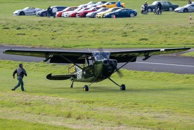 small aircraft and classic cars in background